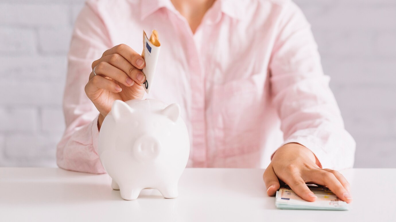 A woman puts money in a piggy bank