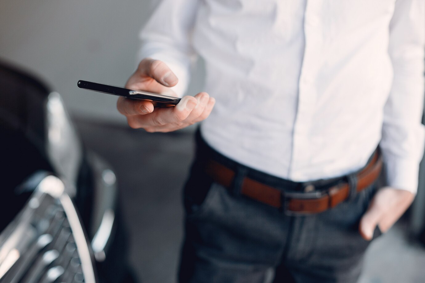 A man in a white shirt holds a cell phone