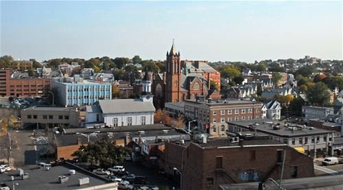 This photo captures a panoramic view of Everett, a charming urban town that blends history and modernity. The centerpiece is a striking red-brick Gothic-style church, its tall spires reaching toward the sky, standing as a testament to the town’s rich architectural heritage.