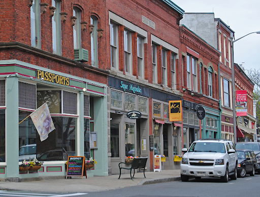 Close-up of red-brick storefronts in Gloucester, MA, showcasing small businesses and colorful signage