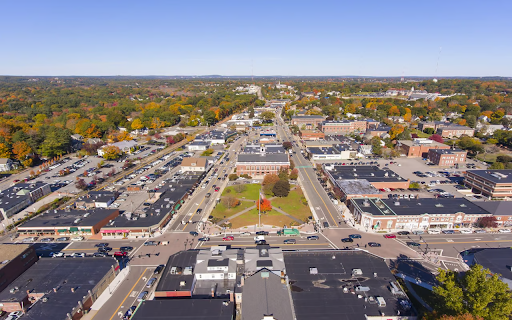 Aerial view of Needham, MA, highlighting its commercial area and town center with surrounding greenery